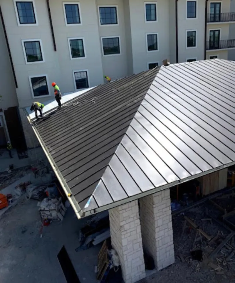 Crew installing standing seam metal roof panels on a commercial project in Jenks